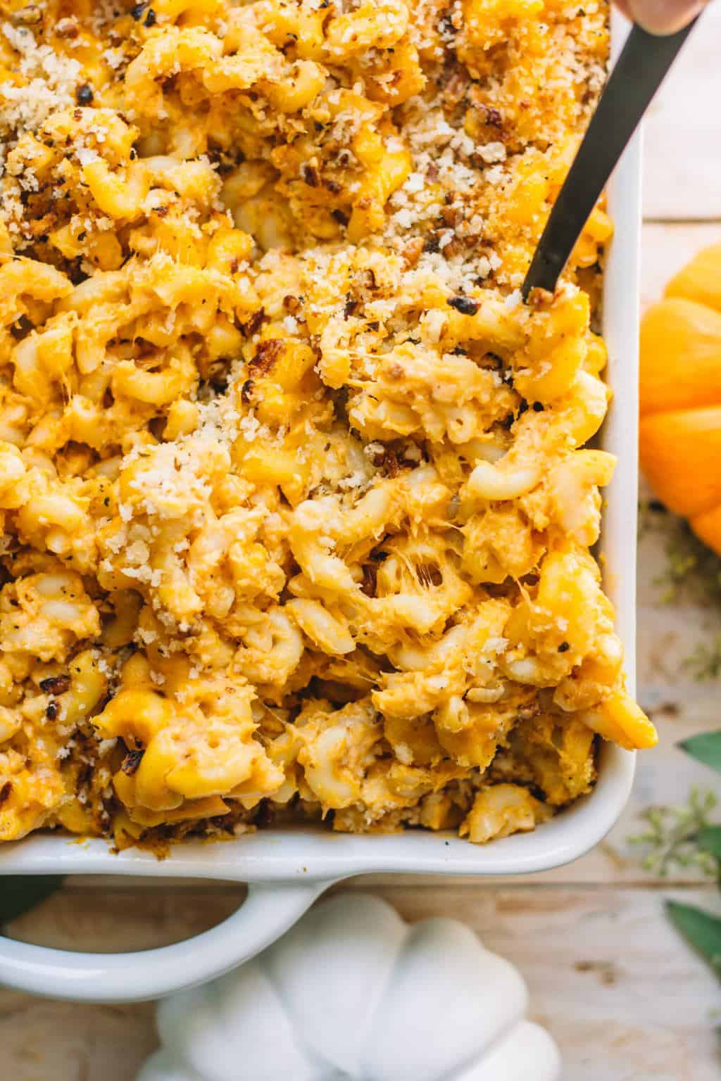 A scoop of pumpkin mac and cheese being scooped for a serving.