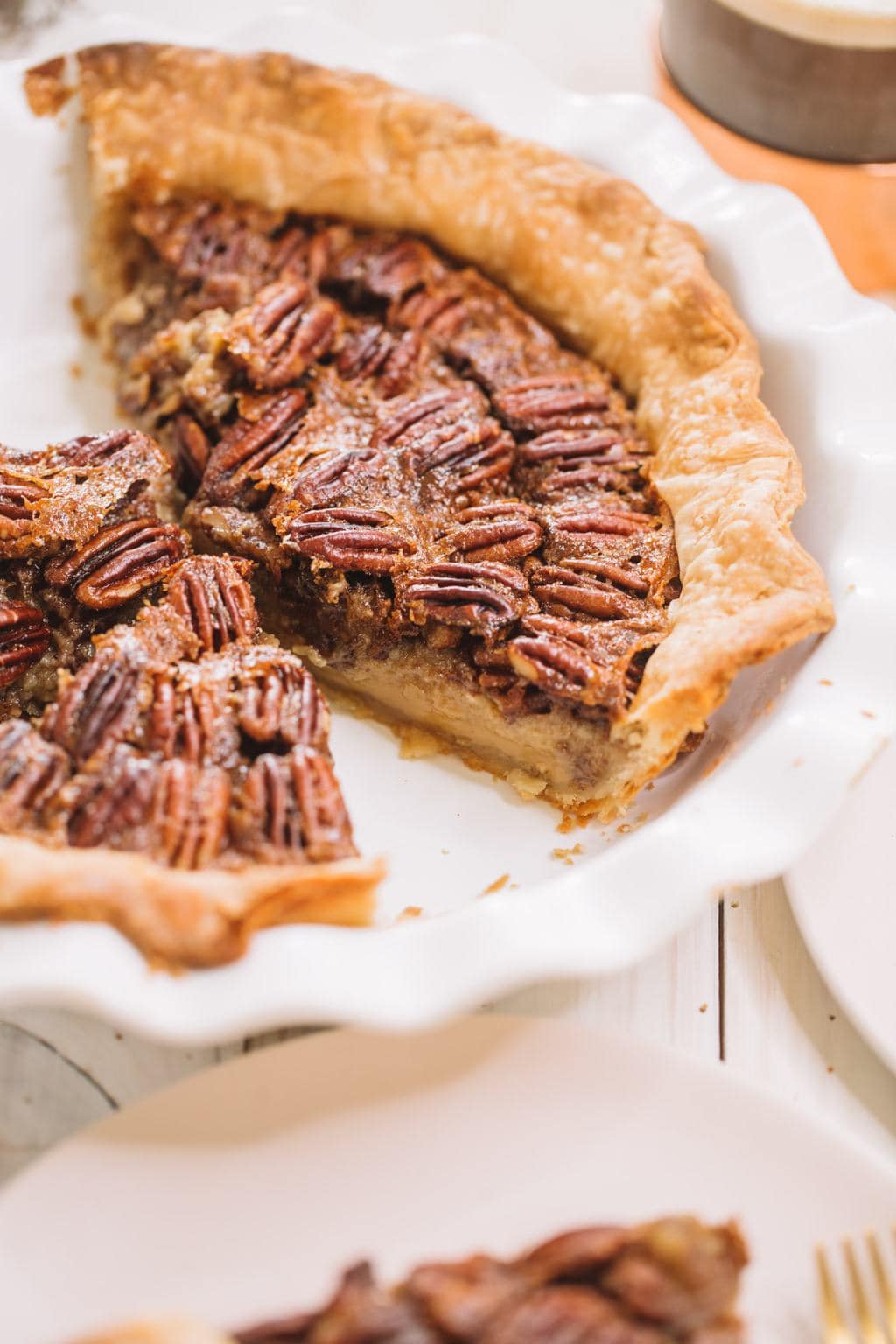 simple pecan pie recipe in white pie dish with two slices removed