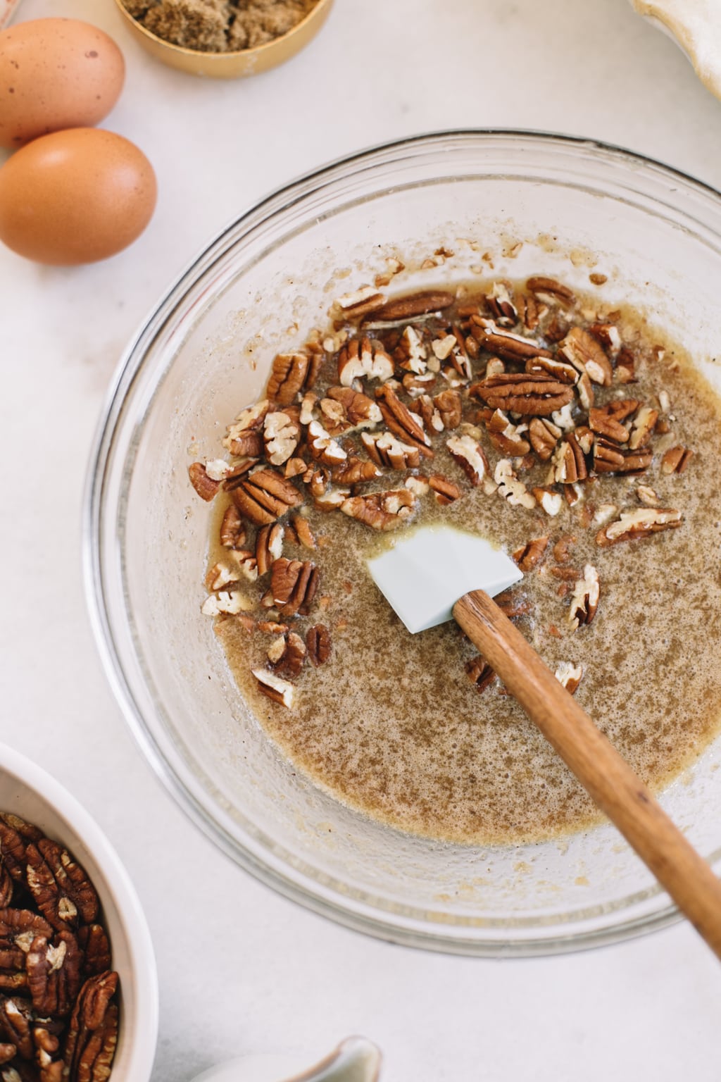 pecan pie filling with brown sugar and maple syrup in glass bowl with spatula