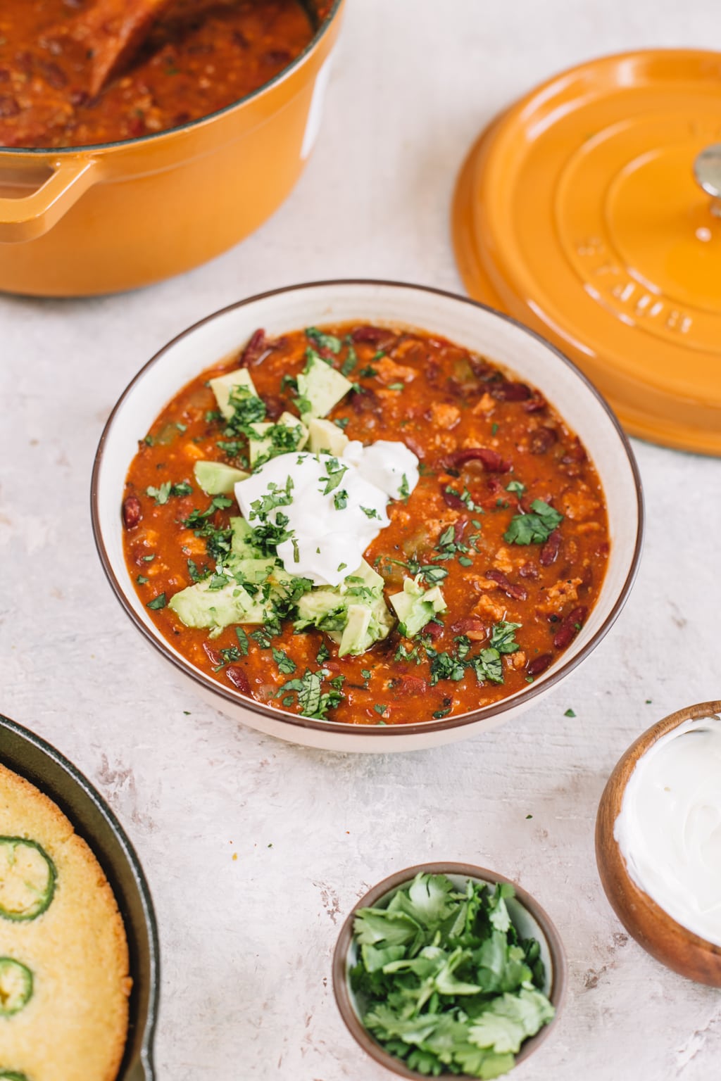 easy smoky chipotle turkey chili in white bowl with yellow dutch oven lid