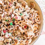 white chocolate chex mix recipe in large bowl with spoon and Christmas ribbon