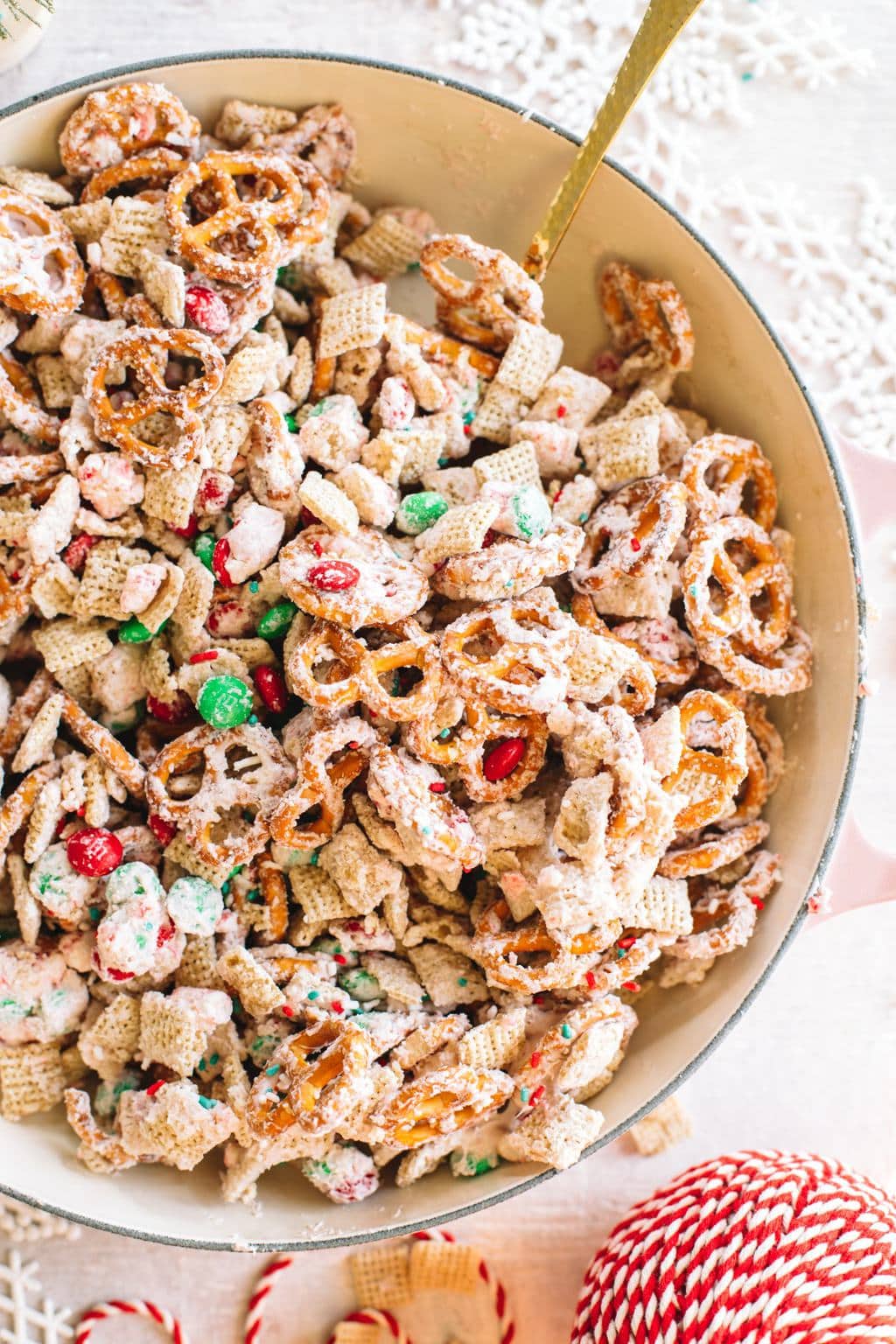 white chocolate chex mix recipe in large bowl with spoon and Christmas ribbon