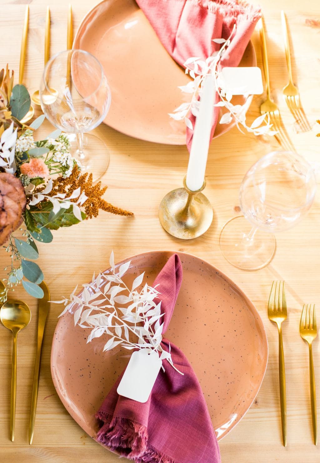 Table setting with peach plate, burgundy napkin and and gold flatware.