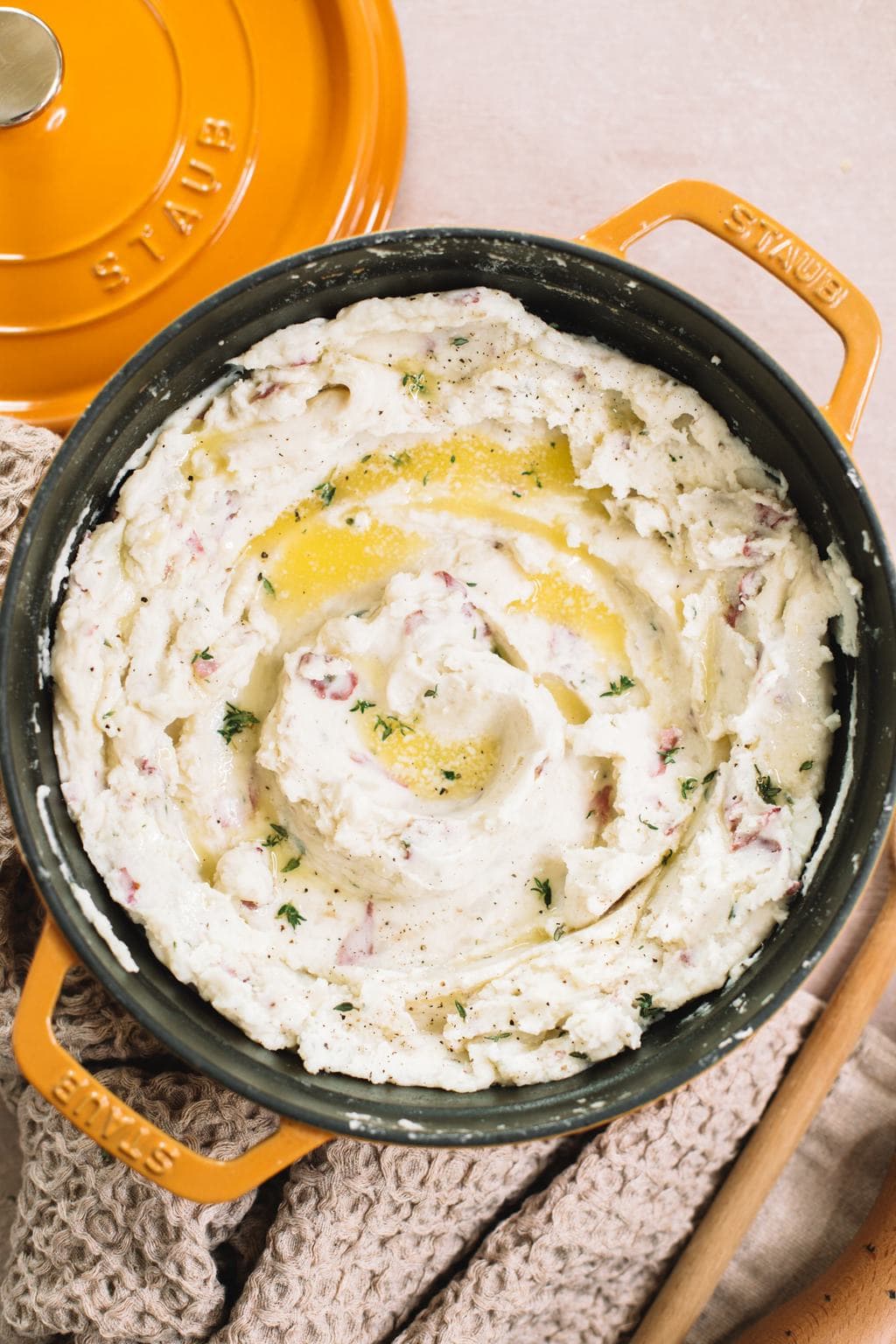 garlic mashed red potatoes in yellow dutch oven with melted butter on top