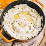 easy garlic mashed red potatoes in yellow dutch oven with melted butter on top