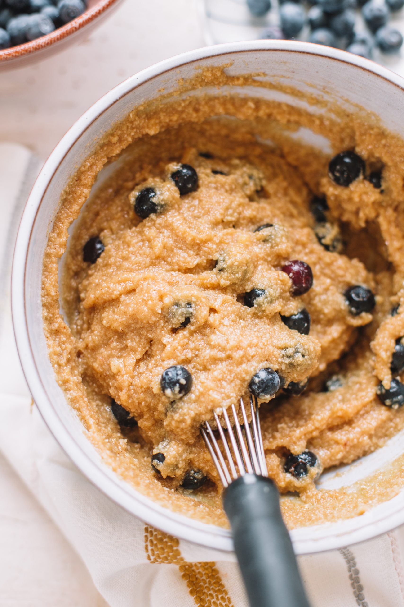 gluten free almond flour blueberry muffin dough in bowl with whisk