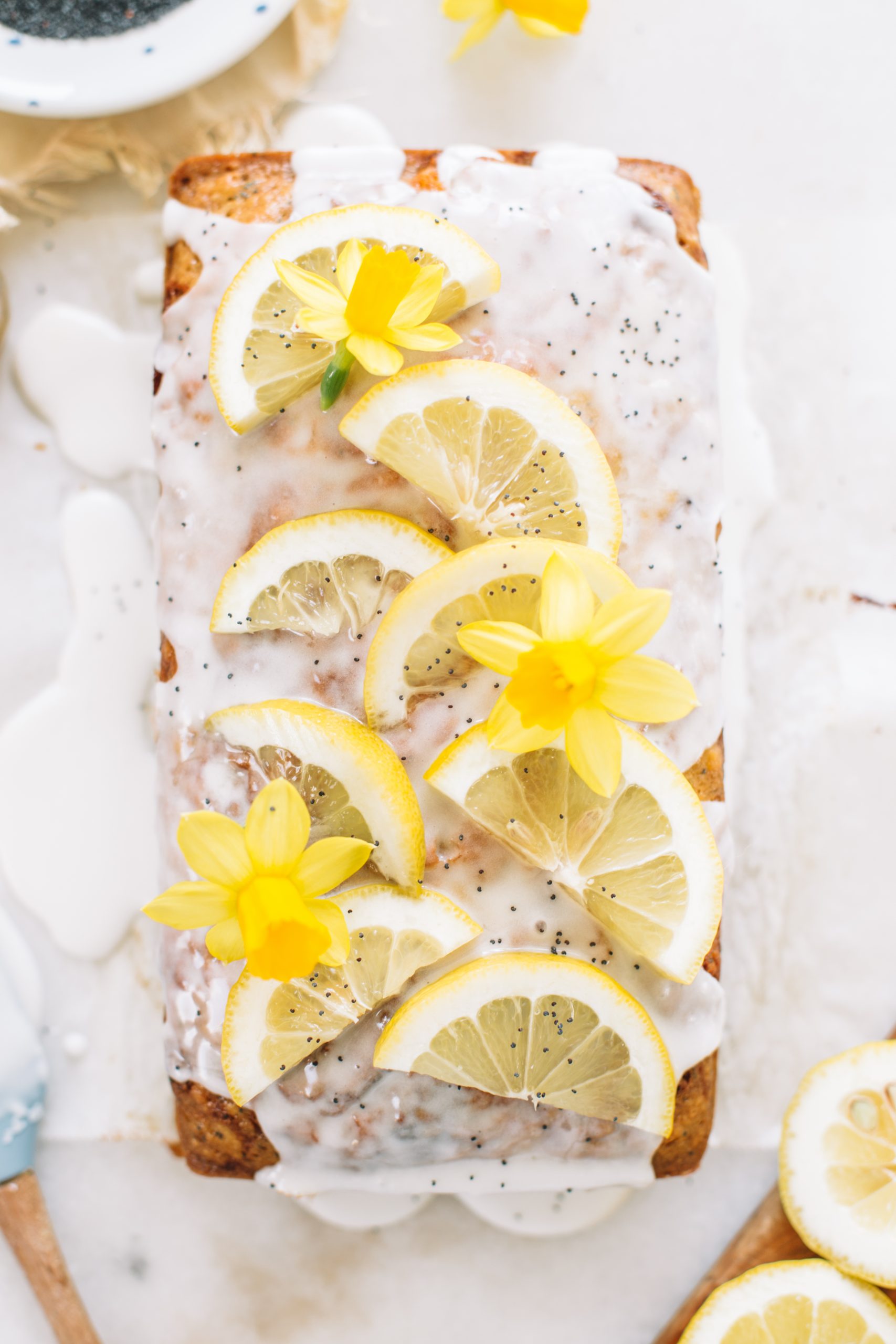a loaf of lemon poppy seed bread with lemon slices and flowers on top