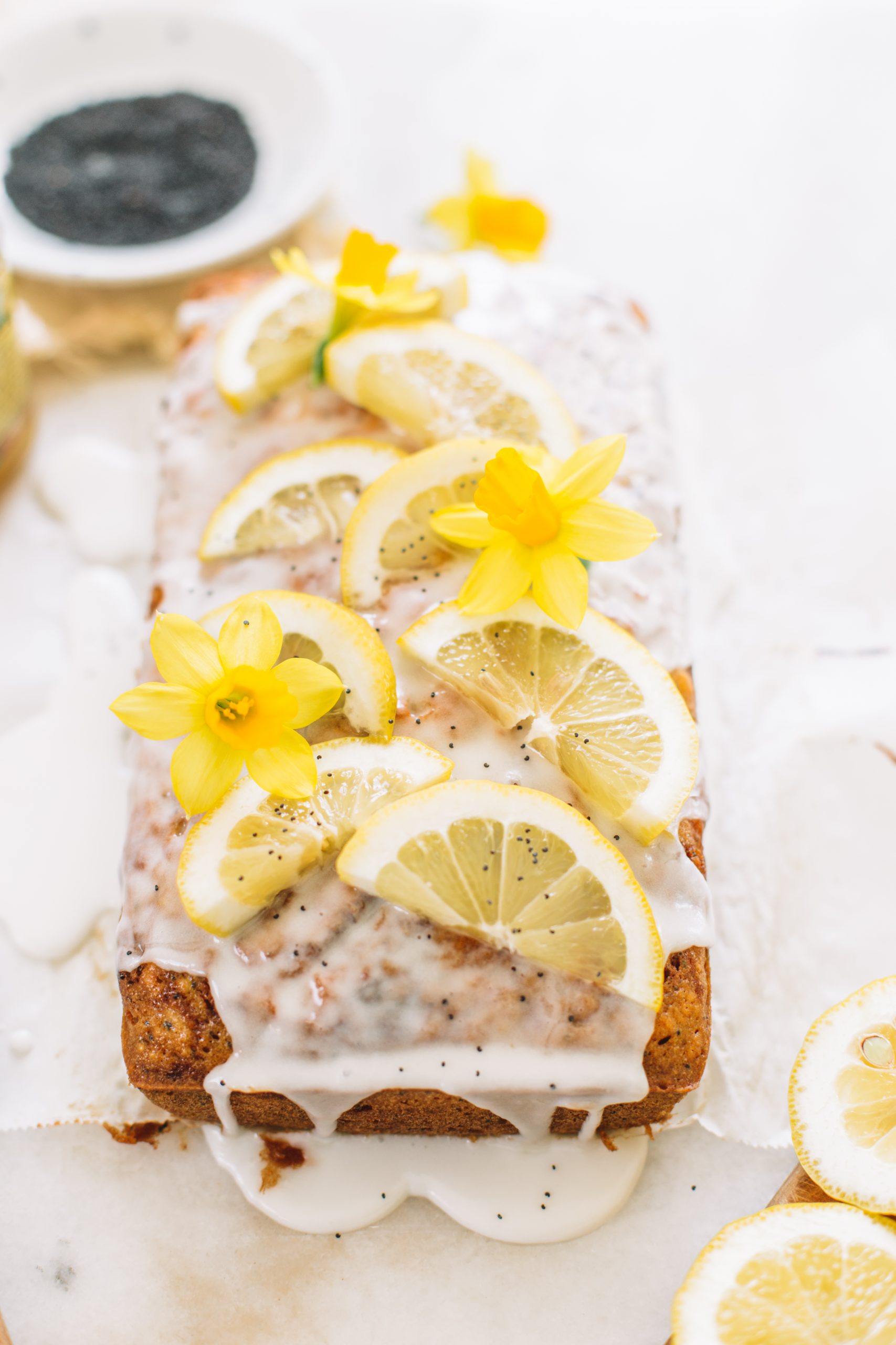 Lemon Poppyseed Loaf Cake topped with lemon glaze, lemon slices and poppy seeds.