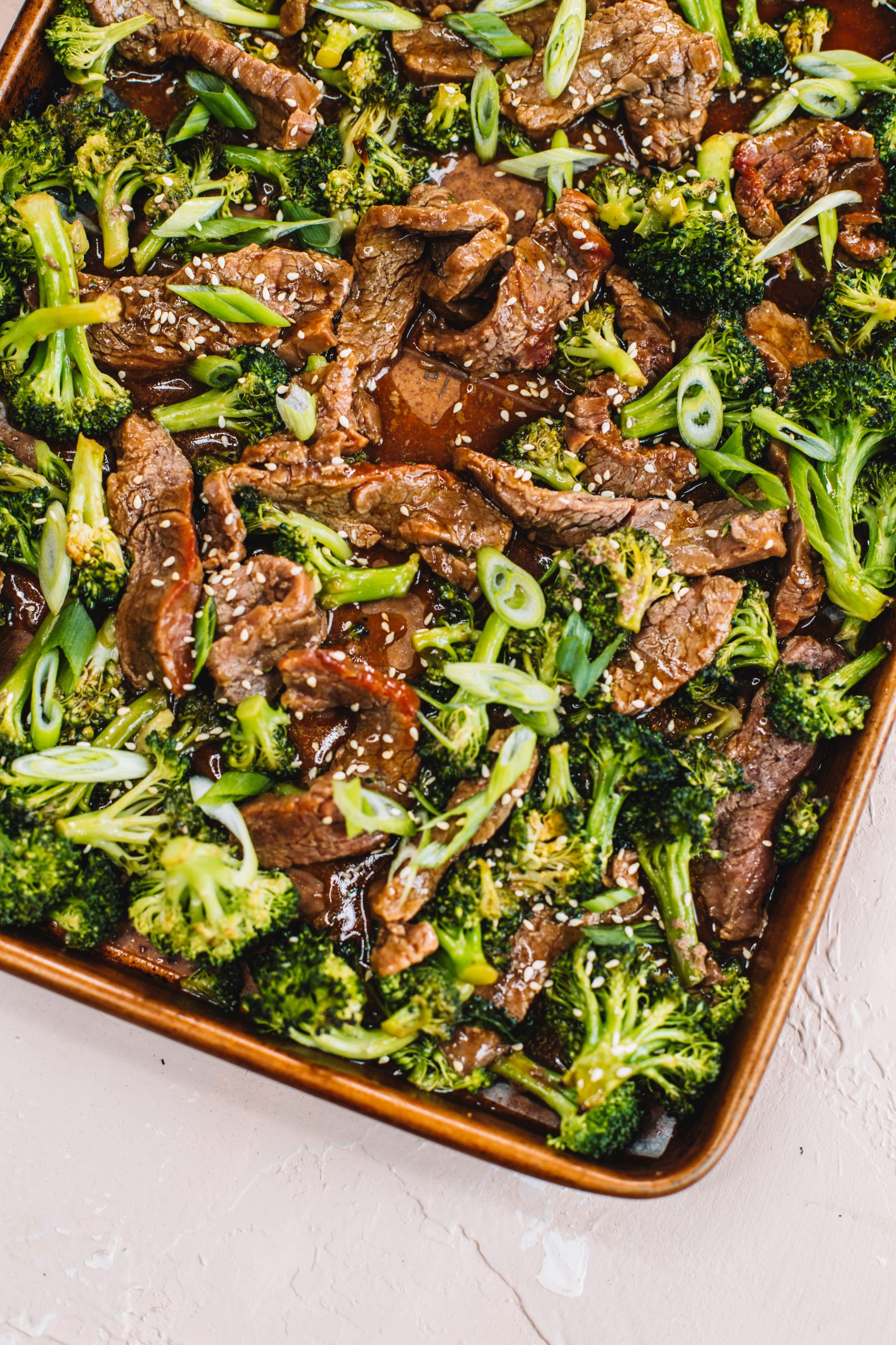 A copper sheet pan filled with Sheet Pan Beef and Broccoli.