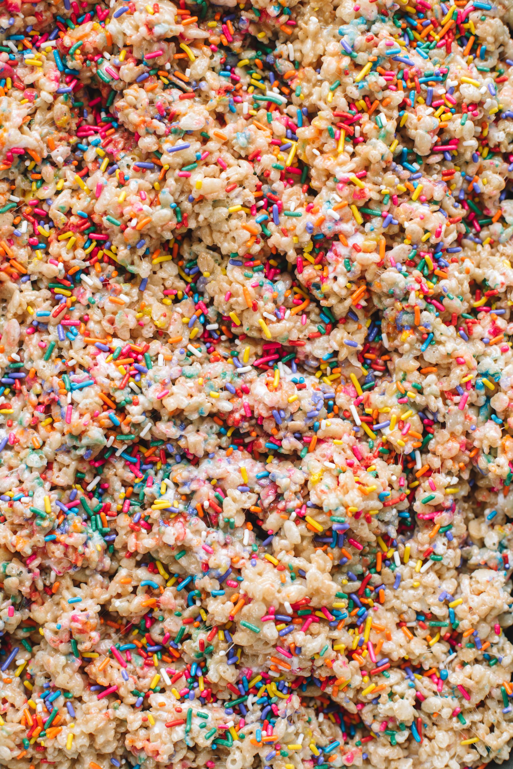 Rice krispie treats drizzled with rainbow sprinkles.