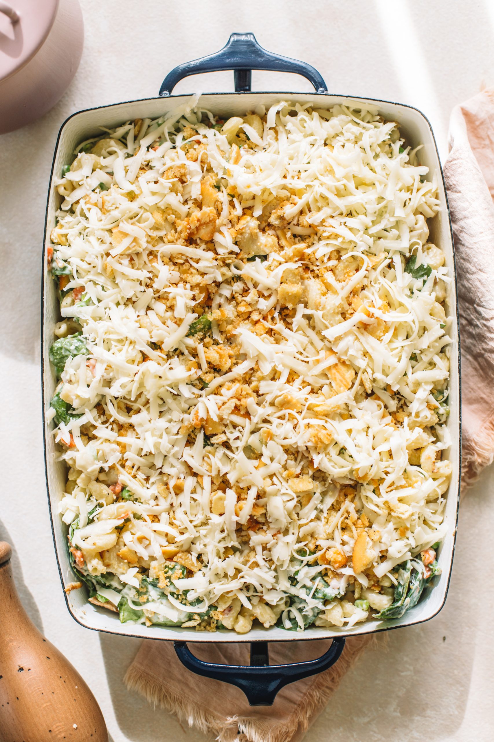 Tuna noodle casserole from scratch topped with cracker topping and cheese ready to go into the oven.