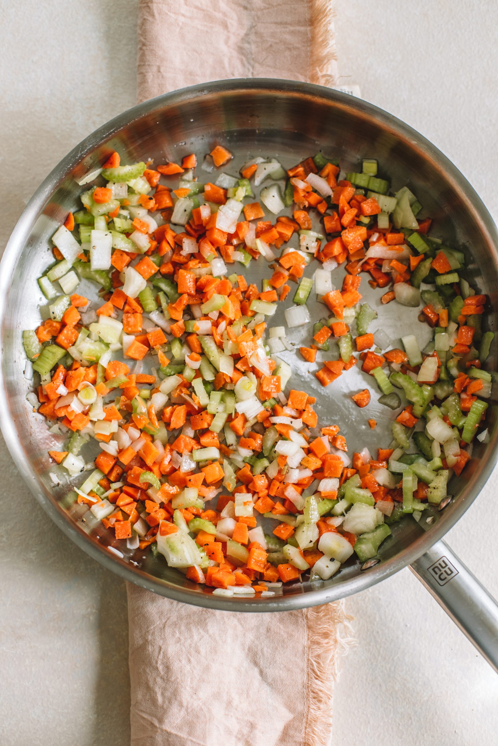 Onions, celery, and carrots being sautéed for tuna noodle casserole recipe. 