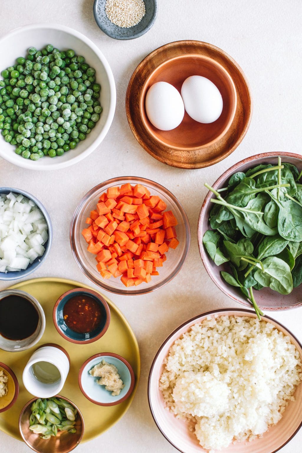 Ingredients in different sized bowls for cauliflower fried rice. 