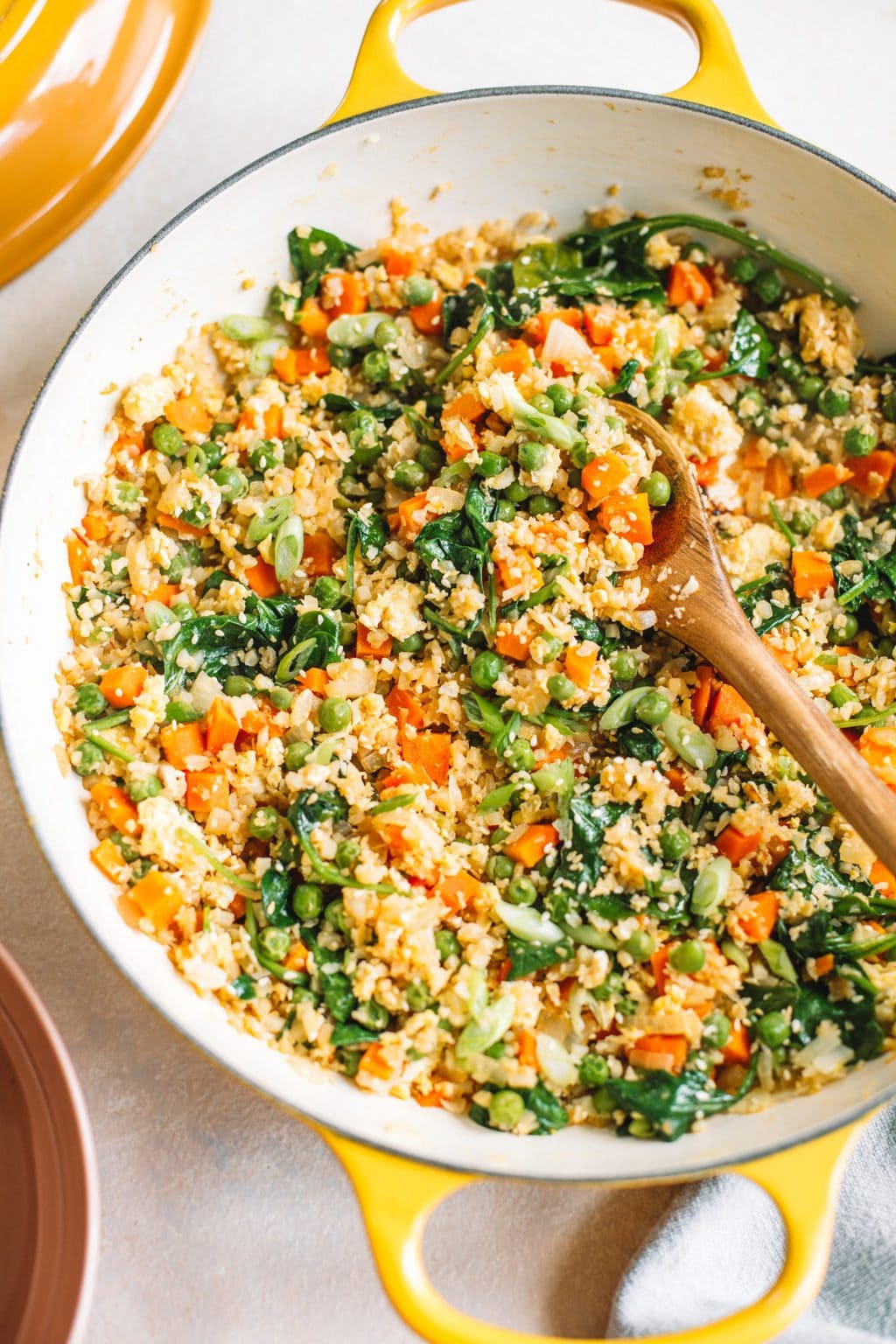 A yellow skillet filled with cauliflower fried rice.