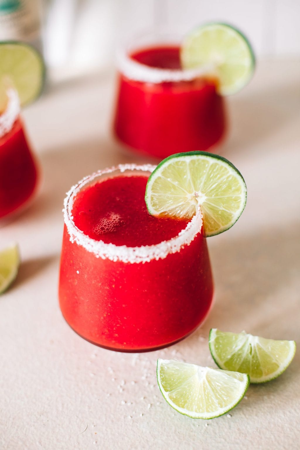 frozen strawberry margarita recipe in glass with salted rim and lime wheel