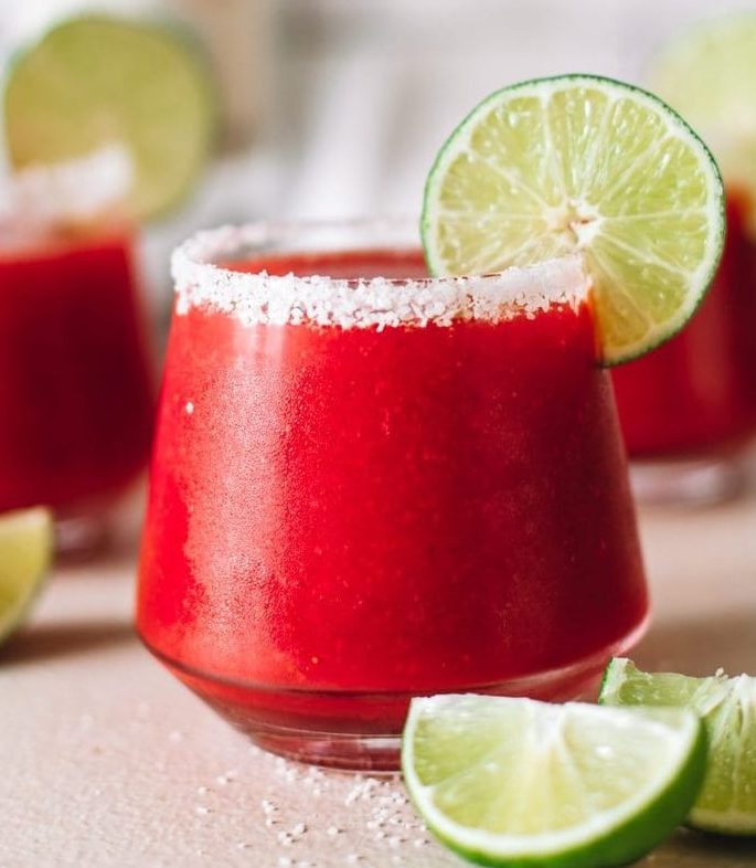 frozen strawberry margarita blended cocktail in glass with salt rim and lime wheel