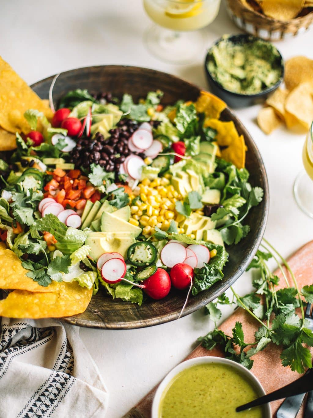 A large mexican tostada salad served in a large wooden serving bowl. 