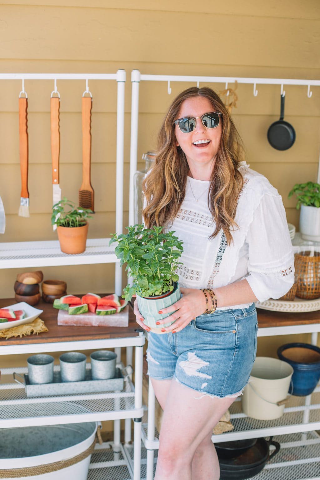 An outdoor buffet setup with a girl holding a mint plant with a turquoise pot.