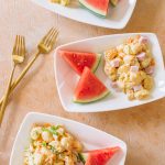 Macaroni salad served on small white dishes with watermelon pieces.