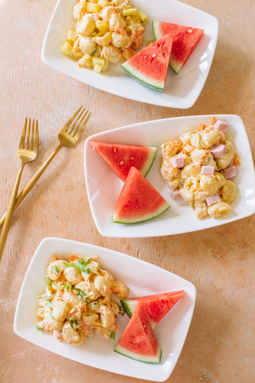 Macaroni salad served on small white dishes with watermelon pieces.