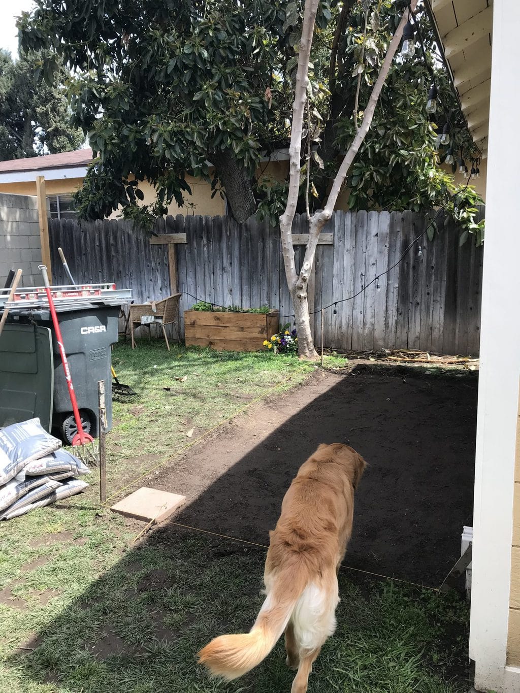 A dirt area of the yard getting ready for grey pavers to be installed.