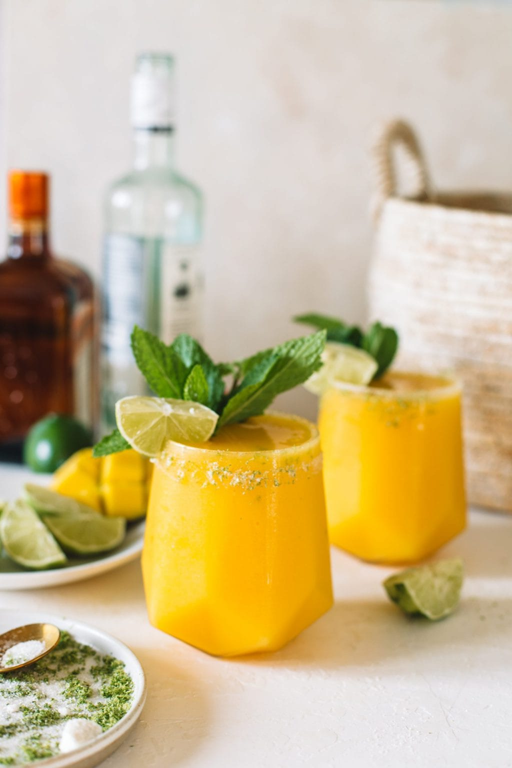 Mango daiquiris in a low glass with a lime wedge and a mint sprig.