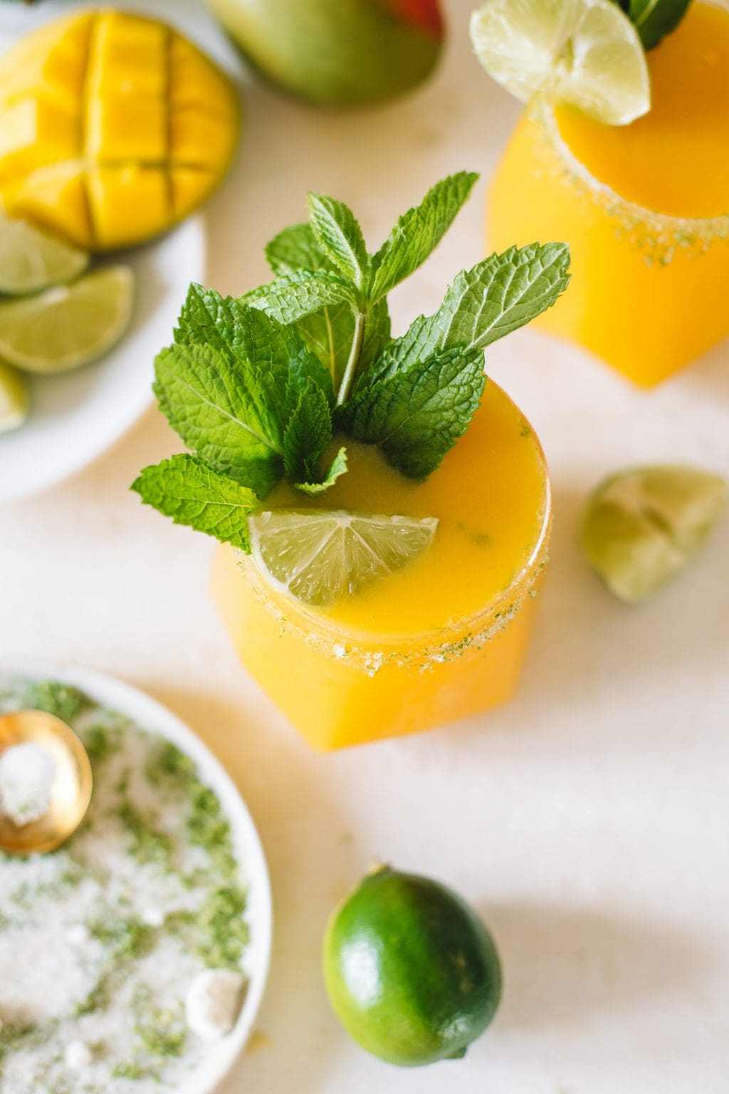 A frozen mango daiquiri with a fresh mint sprig and a lime wedge. 