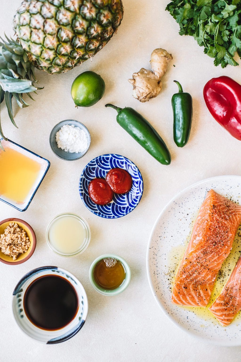 Pineapple juice, corn starch, ginger, garlic, soy sauce, honey, salmon filets and peppers spread out and in little bowls.