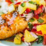 Salmon filet with pineapple glaze and topped with pineapple salsa in a blue bowl.