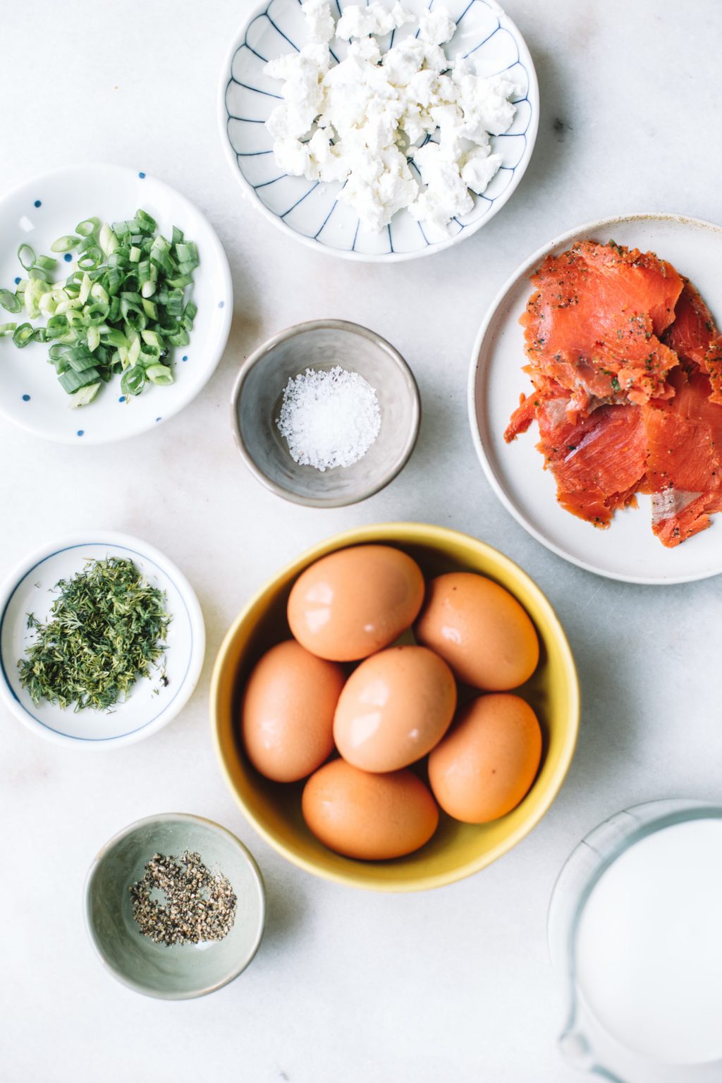 Ingredients for smoked salmon quiche in small bowls and plates.