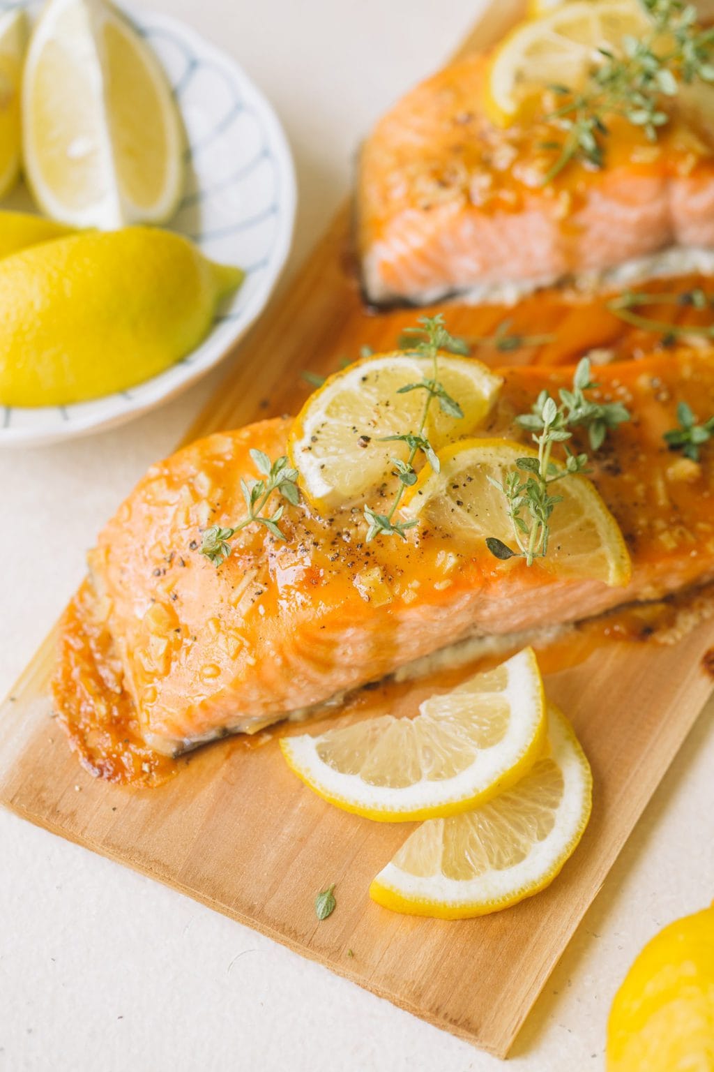 glazed salmon fillets with lemon slices and fresh thyme on cedar plank