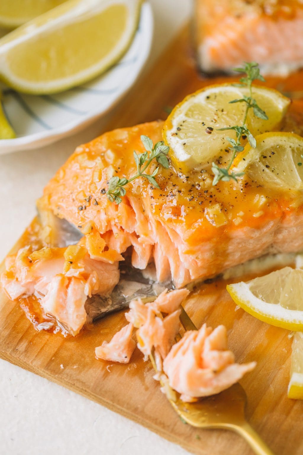 flaked salmon fillet topped with lemon slices and fresh thyme on cedar wood plank