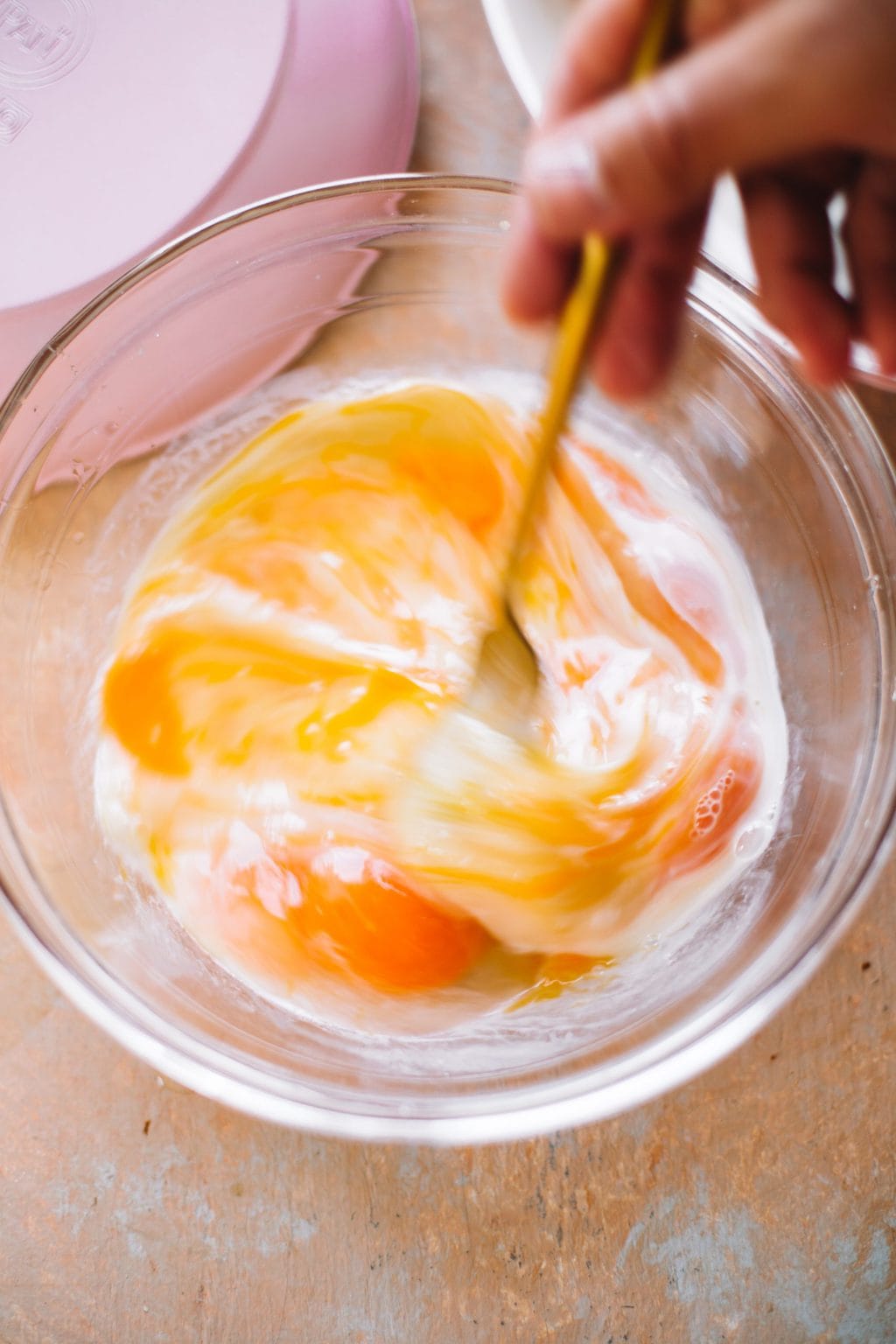 hand whisking eggs and cream in glass bowl