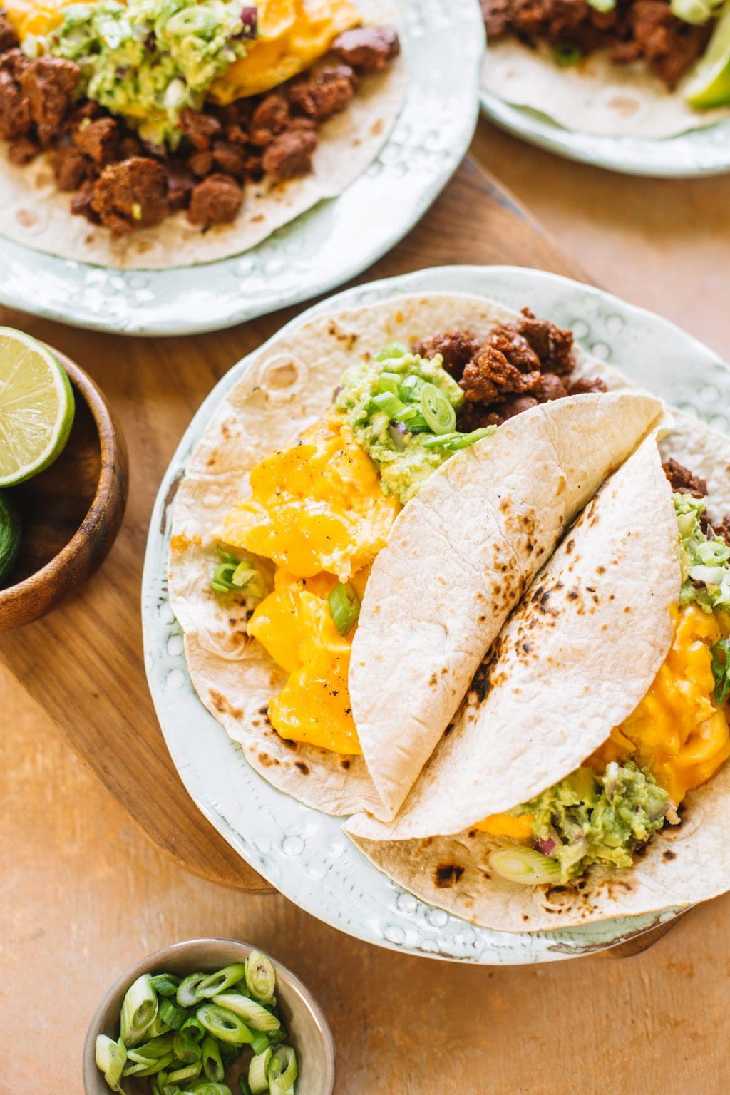 two chorizo and egg tacos folding on white plate