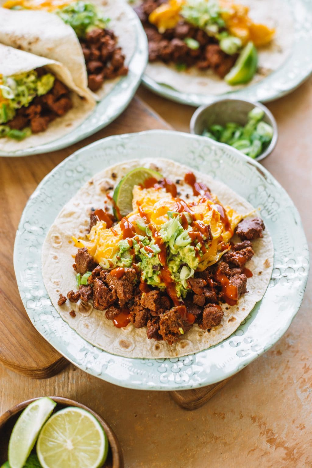 chorizo and egg taco with avocado and hot sauce on white plate