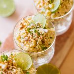 Mexican corn in a cup topped with lime wheels, cotija cheese and cilantro.