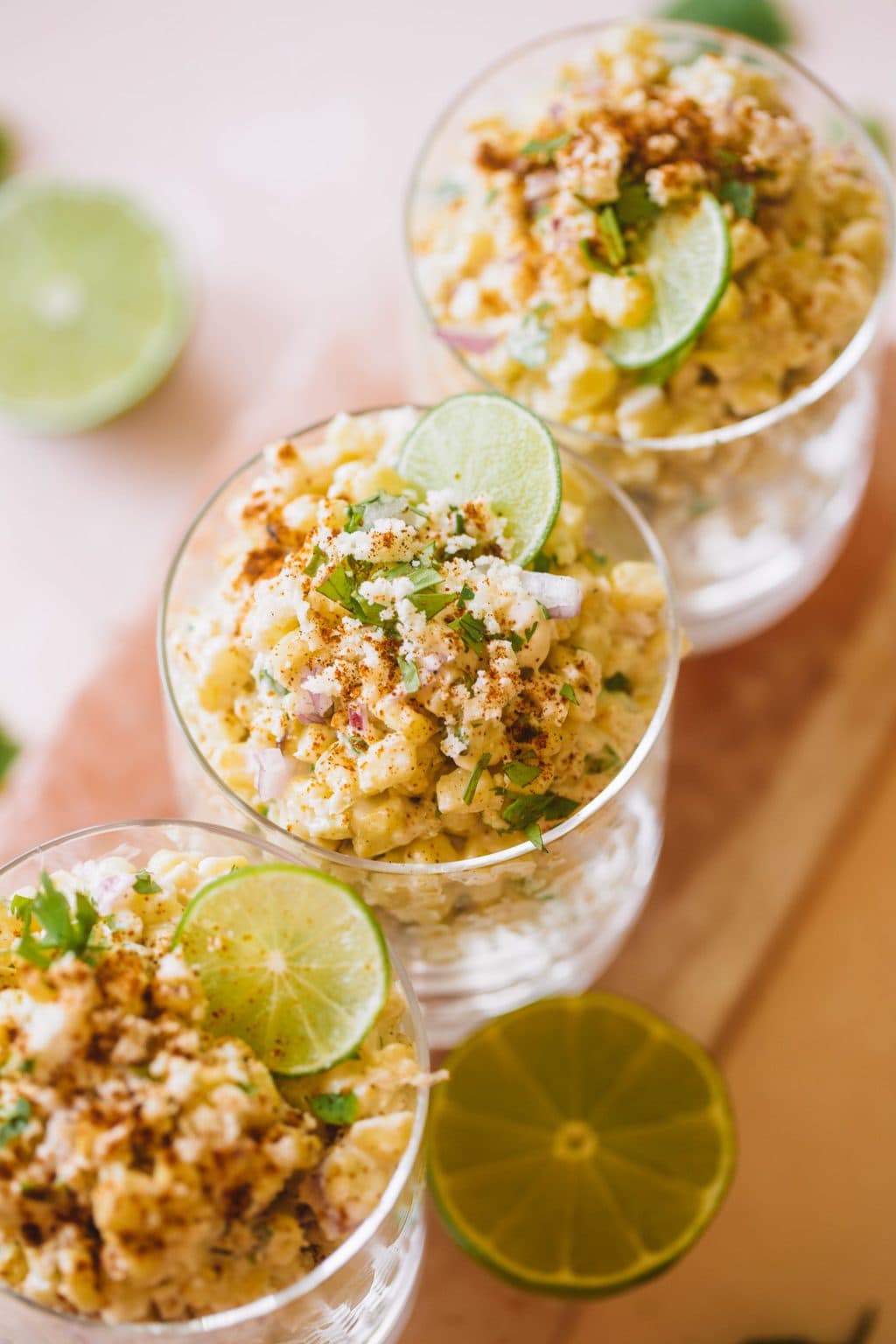 Three cups filled with mexican corn and topped with a lime wheel. 