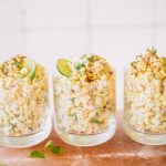 Mexican corn in a cup topped with lime wheels, cotija cheese and cilantro.