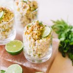 Mexican corn in a cup topped with cotija cheese, chili powder and a lime wheel.