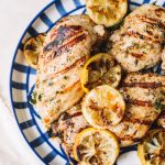 grilled lemon chicken with lemon wheels on blue striped plate