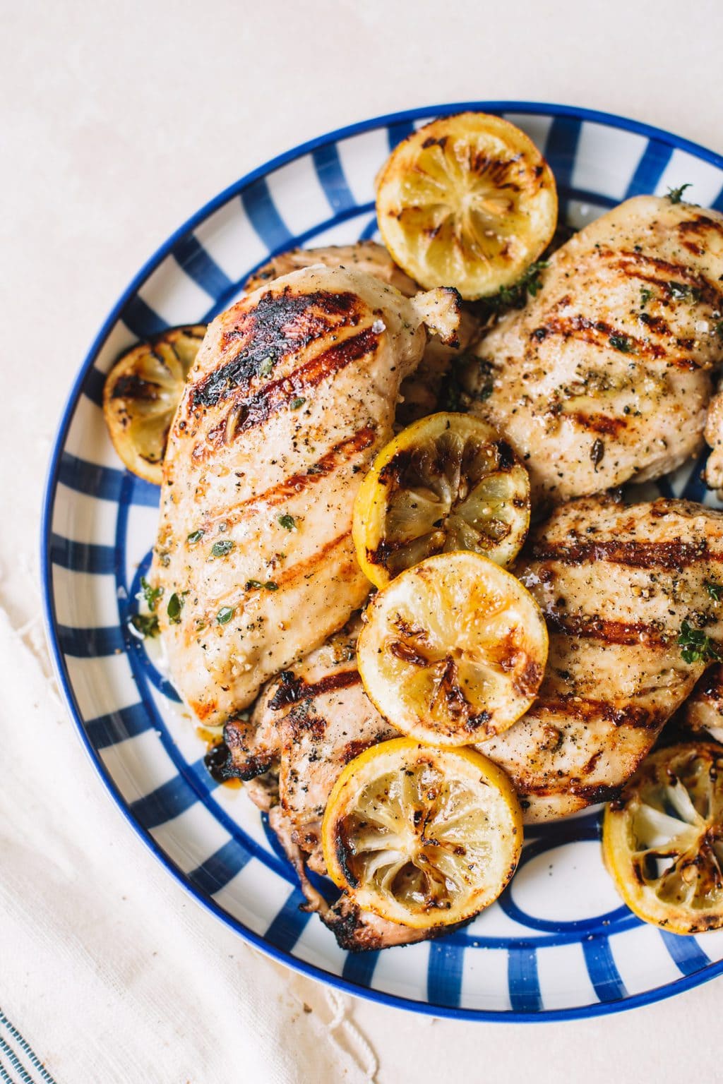 grilled lemon chicken with lemon wheels on blue striped plate