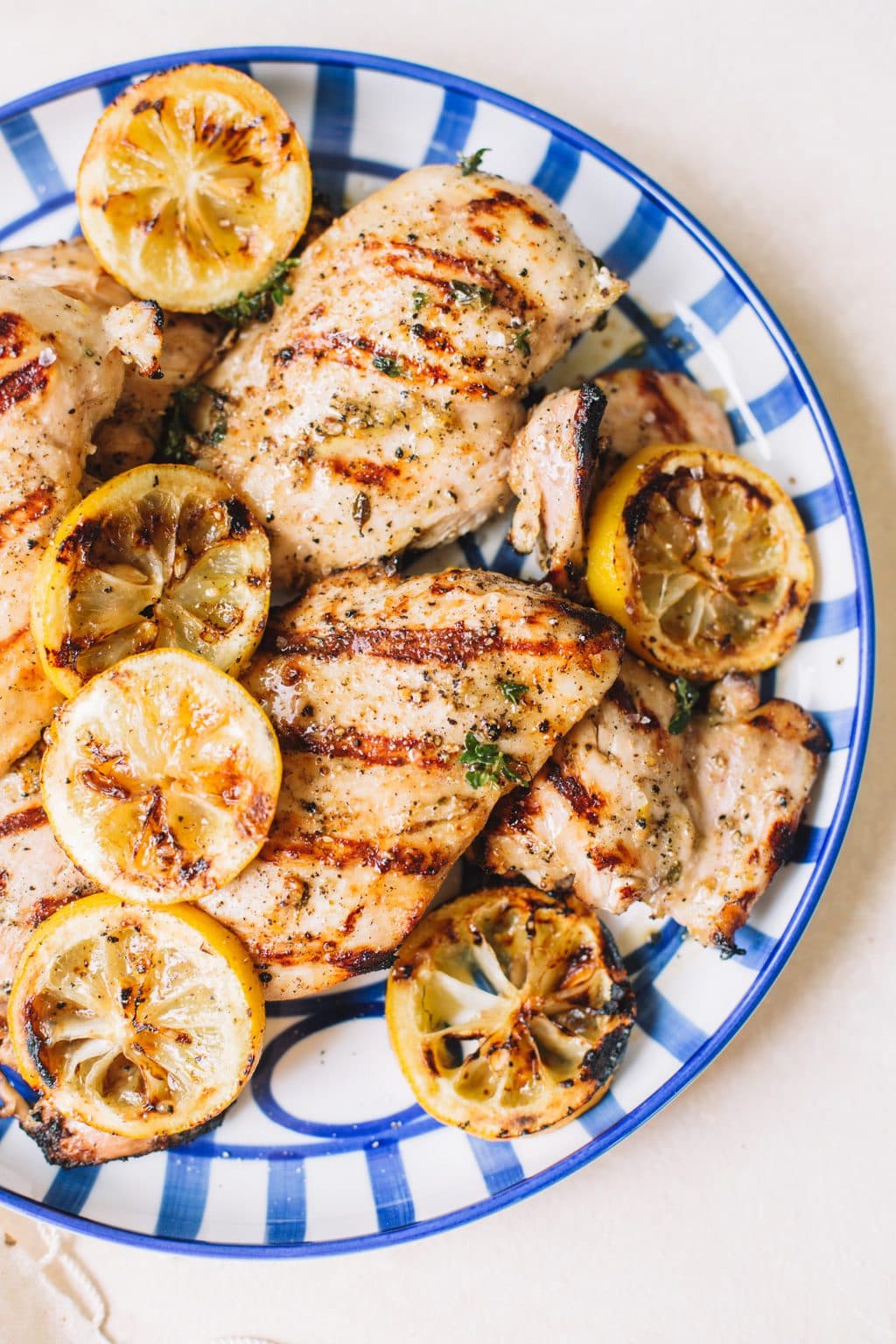 grilled lemon chicken with lemon wheels on blue striped plate