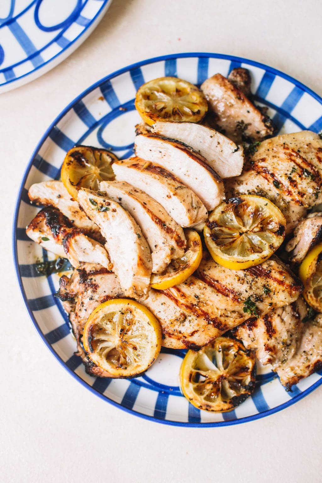 sliced lemon chicken recipe with lemon wheels on blue striped plate