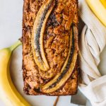 Banana bread baked with two sliced bananas on top.