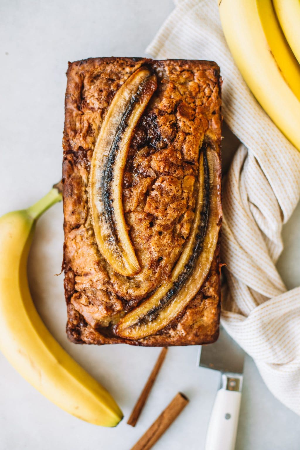 Banana bread baked with two sliced bananas on top.