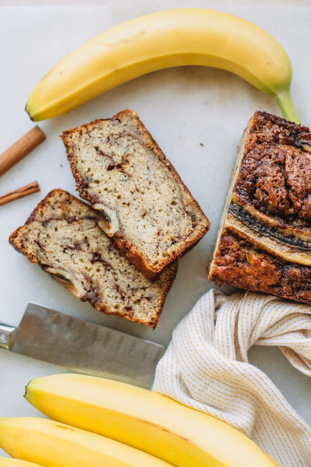 Two slices of cinnamon banana bread next to the whole loaf.