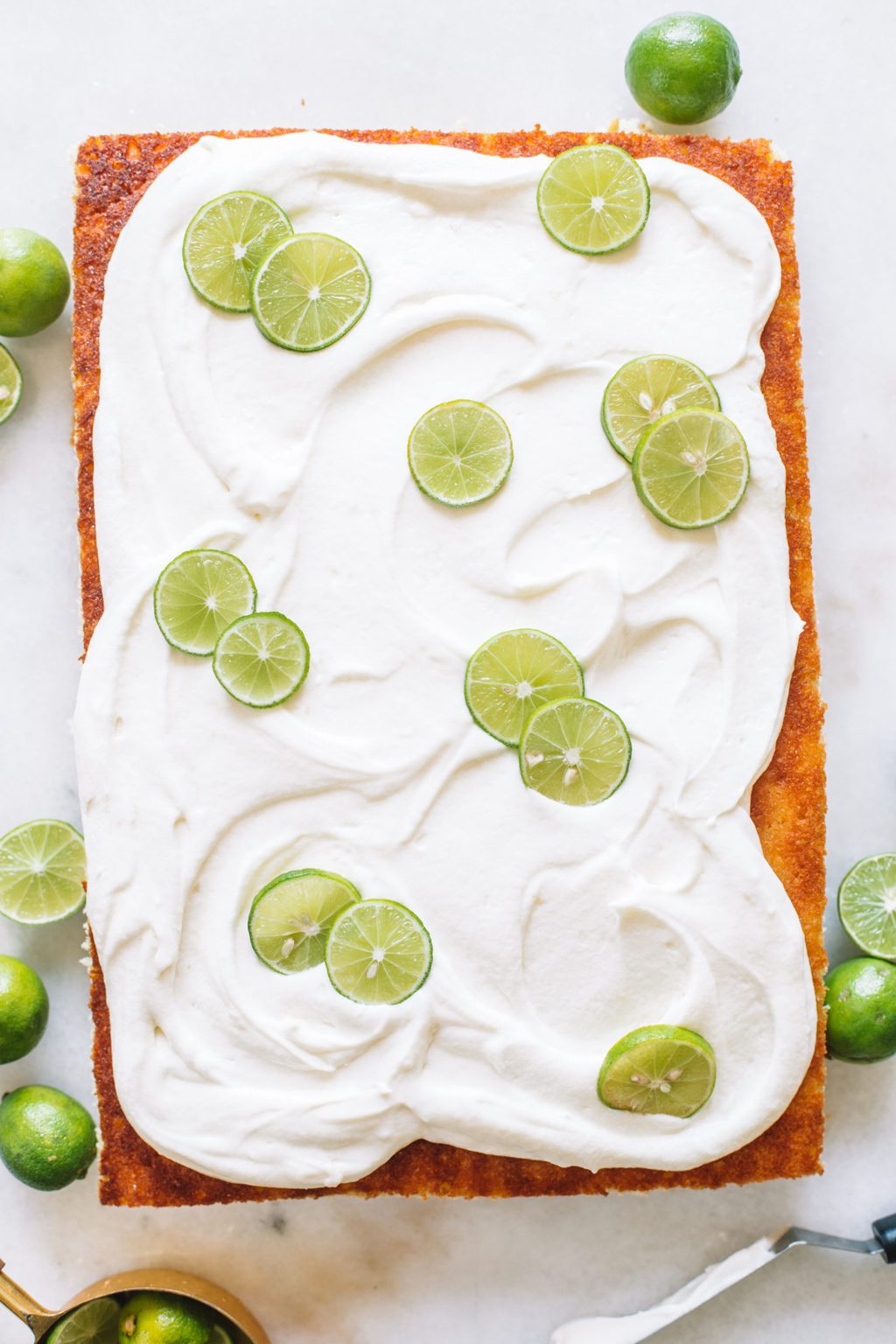 A rectangle sheet pan key lime cake with frosting and key lime wheels.