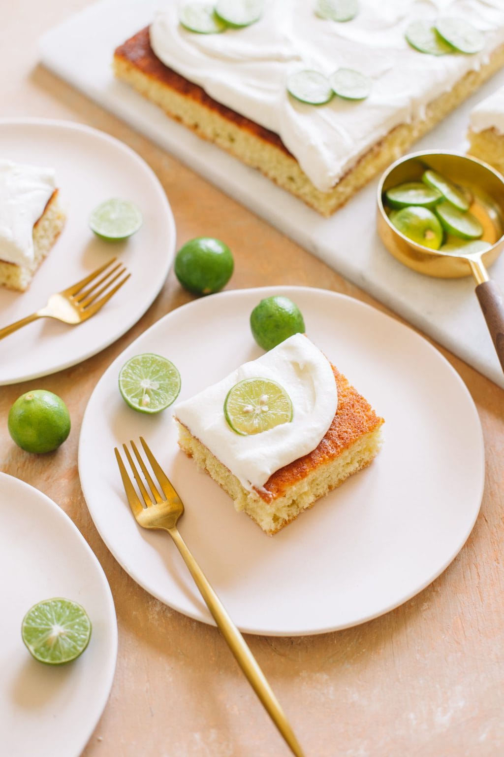 A piece of key lime cake served on a small pink plate with a gold fork.