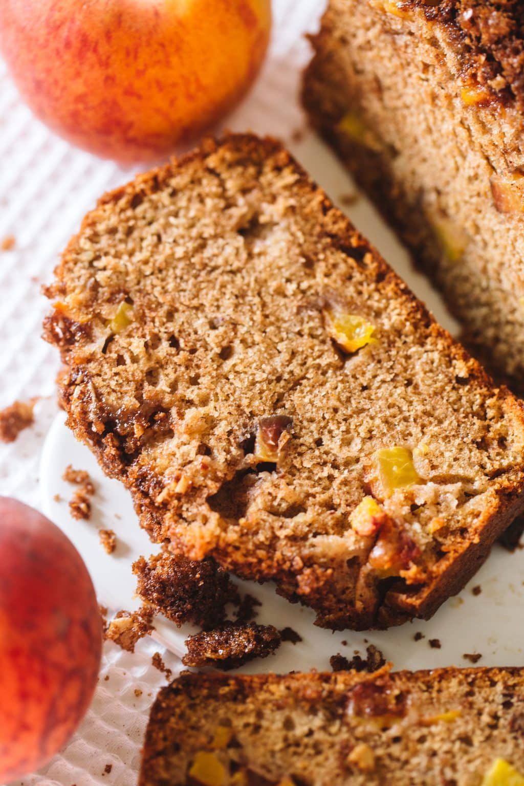 A slice of peach bread with peaches next to it. 