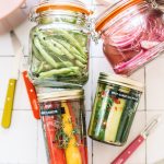 pickled green beans, red onions, carrots and cucumbers in glass jars